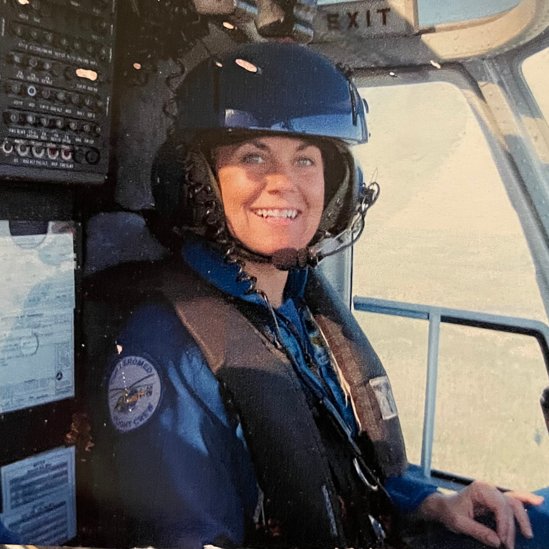 Smiling woman wearing a flight helmet in an aircraft cockpit