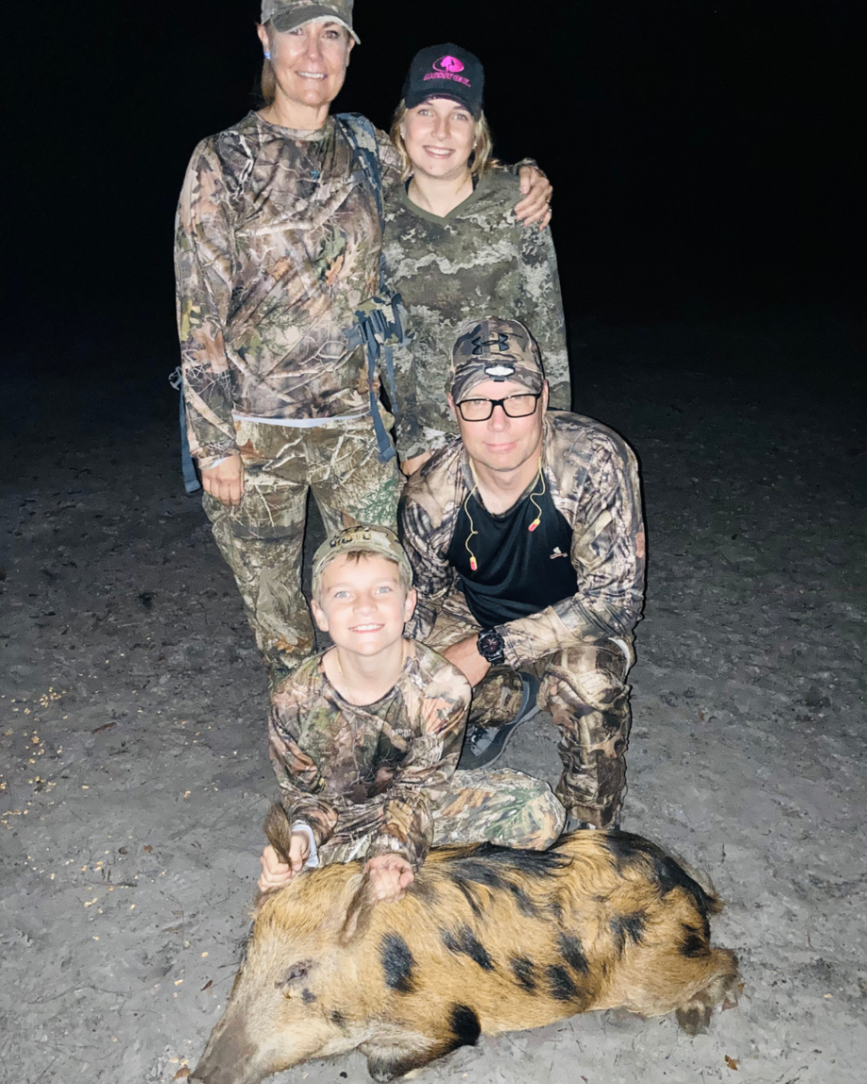 Family of four gathered together after a nighttime wild hog hunt