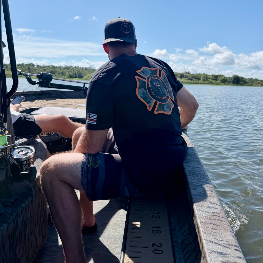 Man wearing an Irons and Antlers shirt and hat while riding in a fishing boat